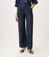 Pantalón de jean azul oscuro de corte recto y tiro alto, inspirado en la sastrería. Presenta pinzas delanteras, bolsillos funcionales y pretina con pasacintos.