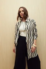 Vestido camisero de corte relajado con estampado de ondas verticales en tonos neutros. Presenta cuello clásico, cierre frontal con botones y mangas largas. Confeccionado en tejido fluido con caída liviana.