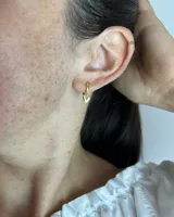 Par de aros tipo huggies dorados con dije colgante de corazón calado.