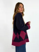 Sweater de cuello alto en color marrón chocolate, con diseño de rombos en la parte inferior en tonos naranja y bordó. Presenta mangas largas con puños acanalados y un corte holgado.