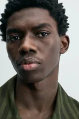 Sobrecamisa de hombre con cuello solapa, manga larga y cierre frontal de botonadura. Presenta un estampado de rayas verticales en tonos de verde oliva y verde oscuro. Incluye bolsillos plastrón en la cadera.