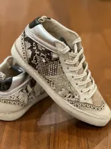 Zapatillas urbanas de media caña, con estampado de piel de pitón en tonos grises y detalles en cuero color crema. Presentan una estrella dorada en el lateral, puntera perforada y cuello acolchado plateado. Suela de goma con efecto envejecido.