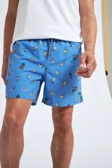 Short de baño con cintura elástica y cordón ajustable, confeccionado en tela ligera de secado rápido. Presenta un estampado botánico integral en tonos amarillos, blancos y azules, con dos bolsillos delanteros y uno posterior.