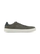 Sneaker de gamuza en color gris, con cordones al tono y suela de goma blanca. Presenta un detalle de refuerzo en el talón en color azul oscuro.