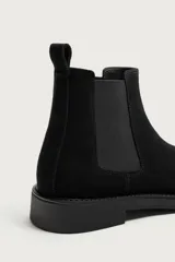 Bota chelsea de hombre en piel con acabado serraje de color negro, paneles elásticos laterales, puntera redonda y suela con ligero tacón.