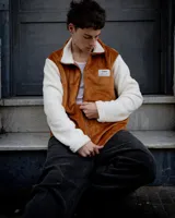 Campera marrón con mangas blancas de peluche con cierre frontal y cuello alto.