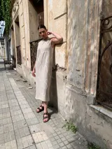 Vestido midi color beige, de corte recto y sin mangas, con estampado de líneas blancas.