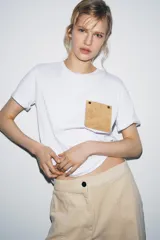 Camiseta blanca de algodón, corte regular, cuello redondo y manga corta, con bolsillo cuadrado de tejido efecto piel color camel en el pecho.
