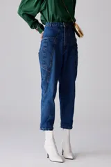 Pantalón de jean azul índigo, tipo cargo, con bolsillos laterales, de tiro medio, con botón negro metálico y diseño de boca en el bolsillo.