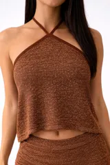 Top corto color marrón con lurex, escote halter cruzado y tejido de punto.