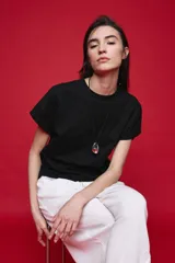 Remera negra de manga corta con cuello redondo y silueta amplia, de hombros caídos y textura suave.