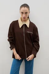 Campera de jean azul oscuro con cuello de pana en color crema. Presenta cierre frontal metálico, bolsillo con cierre en el pecho y bolsillos laterales. Diseño de corte holgado con mangas largas.