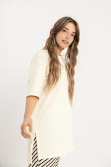 Remerón color crema de tejido acanalado, con cuello redondo, mangas cortas y tajos laterales.