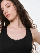 Musculosa de punto pointelle color gris melange, con escote redondo, detalle de picot en los bordes y una pequeña moña decorativa en el centro del pecho.