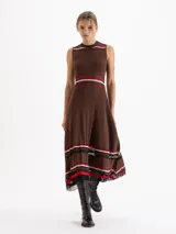 Vestido midi de punto sin mangas con diseño plisado. Presenta un corte evasé con rayas horizontales en tonos rojo, rosa y negro en el cuello, la cintura y el ruedo, el cual cuenta con terminaciones irregulares y detalles de transparencia.