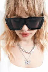 Lentes de sol rectangulares oversized de estilo tecno, con marco negro y cristales oscuros. Ofrecen filtro de protección UV 400 que bloquea rayos UVA y UVB.