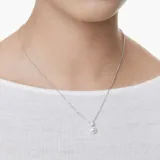 Collar con cadena plateada y dije con perla blanca colgante debajo de un cristal con forma de flor.