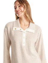 Buzo de tejido soft mohair con estampado zigzag en tonos beige y blanco. Presenta cuello polo, escote en V con botones a presión y manga larga amplia. El bajo tiene tajos laterales y apliques metálicos.