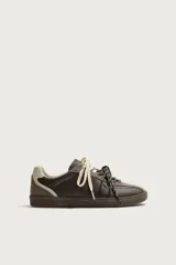 Zapatilla deportiva de estilo retro, confeccionada en una combinación de piezas de cuero texturizado y gamuza en tonos marrones. Presenta un diseño de doble cordonera con cordones claros y suela de goma a tono.