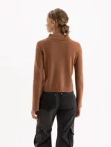 Sweater de punto color rosa, con cuello polo, cierre frontal con botones y mangas largas con puños acampanados.