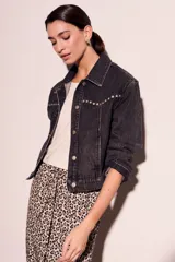 Campera de denim gris oscuro con tachas plateadas en cuello y solapas, corte cropped y mangas largas.