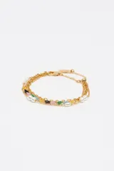 Pulsera de triple cadena dorada con dijes de corazones de cristal en diversos colores y perlas blancas. Posee cierre de mosquetón y cadena ajustable.