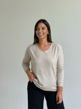 Sweater de punto fino en color beige, con escote en V y mangas largas con puños ajustados.