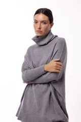 Sweater de punto color gris, con cuello polera amplio y diseño oversize de silueta fluida y caída liviana.