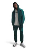 Pantalón jogging Under Armour modelo Unstoppable, color verde oscuro con paneles en tono contrastante y bolsillo lateral con cierre diagonal. Cuenta con cintura elástica y puños en los tobillos.