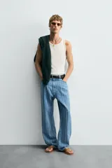 Camiseta tipo tank top de corte slim fit, color blanco hueso, con cuello redondo amplio y sisas terminadas con pespunte contrastante en color oscuro.