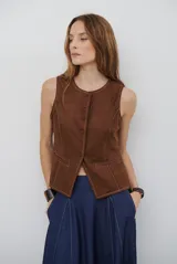 Chaleco de gamuza color caramelo, con cierre frontal de botones y bolsillos laterales simulados.