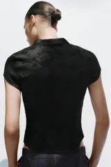 Top negro de manga corta y cuello mao con diseño jacquard de flores, escote en pico y cierre frontal con alamares.