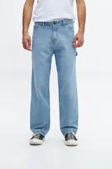 Pantalón de jean celeste, de corte amplio y tiro medio, con bolsillos delanteros y traseros, y presilla para herramientas en la pierna derecha.