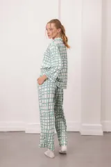 Conjunto de pijama de dos piezas, color verde menta con estampado de cuadros irregulares en blanco. Incluye camisa de manga larga con botones y pantalón largo con cintura elástica.