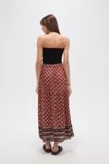 Falda larga de viscosa con estampado en tonos terracota y beige. Presenta un diseño escalonado con un patrón floral repetitivo en la parte principal y un borde inferior con un patrón geométrico en tonos más oscuros. Tiene cintura elástica con cordón ajustable.