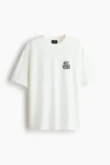 Remera de algodón blanca de corte holgado, con cuello redondo y estampado gráfico en el pecho con la leyenda "Next Level Ready" en color negro.