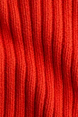 Buzo de punto acanalado en color rojo, con cuello redondo y mangas largas con costuras raglán.