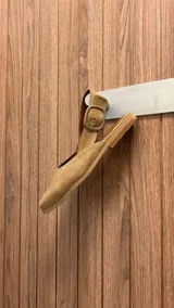 Sandalia chata color tostado de cuero con correa al tobillo con hebilla dorada.