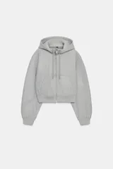 Cazadora de estilo deportivo con capucha ajustable, cierre frontal de doble cremallera y mangas abullonadas con puños elásticos. Presenta bolsillos delanteros y bajo elástico.