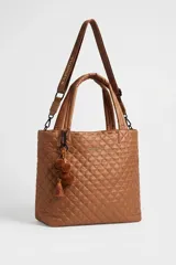 Cartera tote maxi bag color negro, con diseño acolchado y pespuntes en rombos. Cuenta con doble asa de mano, correa ajustable y extraíble, cierre superior y detalle de llavero con pompón y borla colgante.