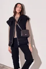 Chaleco negro con cuello de piel sintética, cierre frontal con cremallera y corte oversize.