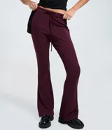 Pantalón de sastrería corte flare, color bordó, con cintura elástica ajustable mediante lazo y detalle de costura vertical (friso) en el frente de las piernas.