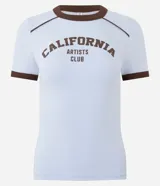 Remera celeste de corte ajustado, con mangas cortas, cuello redondo y ribetes en color marrón oscuro. Presenta la inscripción "California Artists Club" en el pecho en tono marrón.