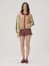 Campera estilo bomber Mutma Satifo, de diseño colorblock con cuerpo en color óxido y mangas celestes con detalles en azul marino. Cuenta con cuello camisero, cierre frontal, puños y ruedo elásticos rayados, y un parche gráfico en el pecho.
