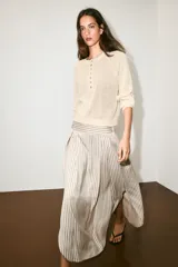 Sweater de punto color beige con cuello redondo, manga larga y cierre frontal parcial con botones. Presenta terminaciones en rib en cuello, puños y dobladillo.