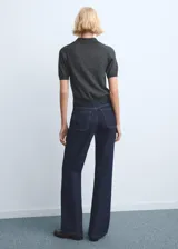 Jeans tiro medio de corte recto, color azul oscuro, con bolsillos laterales y traseros, costuras en contraste y cierre frontal con botón y cremallera.