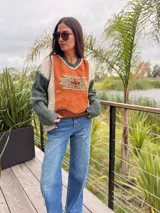 Sweater de diseño artesanal con frente de cuero en color naranja con aplique geométrico, y mangas y espalda tejidas en combinación de colores verde y beige. Presenta cuello en V y corte holgado.