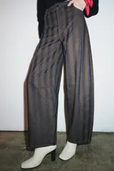 Jeans de tiro medio con corte barrel leg, confeccionados en denim con rayas verticales a contraste en tonos azul oscuro y marrón/tostado. Presentan cinco bolsillos y cierre frontal con cremallera y botón.