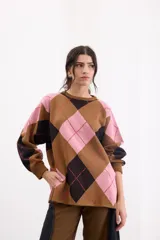 Sweater holgado con diseño de rombos en tonos marrón, negro y rosado, con detalles de lurex en las líneas divisorias. Presenta cuello redondo, mangas largas con puños acanalados y un corte relajado.