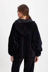 Campera de terciopelo color chocolate, con corte holgado, mangas murciélago y capucha desmontable. Presenta cierre frontal con botones a presión y bolsillos laterales.